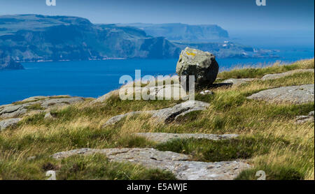 La Côte d'Antrim N vu depuis le chemin de l'Homme gris tête juste Co Antrim N Irlande avec un bloc erratique glaciaire dans l'avant-plan Banque D'Images