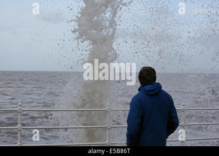 Un homme d'Aberystwyth se tient devant une mer déchaînée pendant les tempêtes de 2014 Banque D'Images