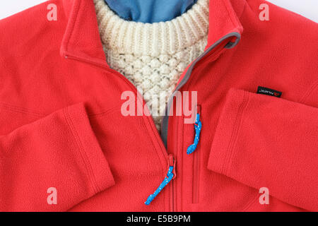 Veste polaire Polartec rouge avec zip ouvert sur un chandail Arran pour vêtements d'hiver chauds. En Angleterre, Royaume-Uni, Angleterre Banque D'Images