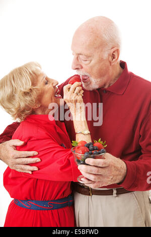 Romantic senior couple flux à chaque d'autres petits fruits sains. Fond blanc Banque D'Images