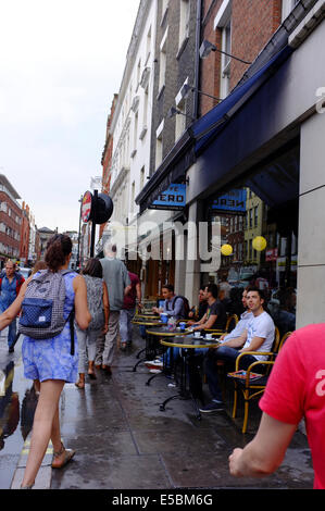 Les buveurs de café en plein air sur la chaussée encombrée au Caffe Nero à Soho, Londres Banque D'Images