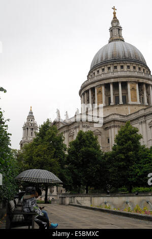 Couple de touristes à l'abri de la pluie sous un parapluie à Saint Paul's Cathedral, London Banque D'Images