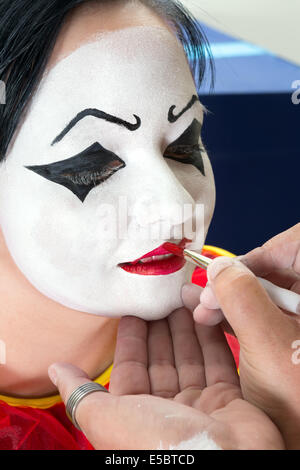 Pierrot clown woman getting son visage peint Banque D'Images