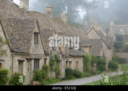 L'Arlington Row, tisserands couleur miel cottages dans le brouillard du matin dans la ville de Bibury dans Gloucestershire dans la région des Cotswolds. Banque D'Images