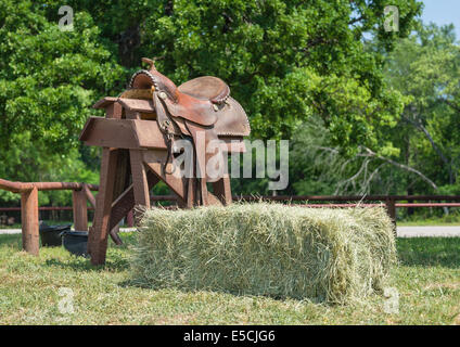 Selle de cheval en cuir affiche sur un support en bois et une balle de foin Banque D'Images