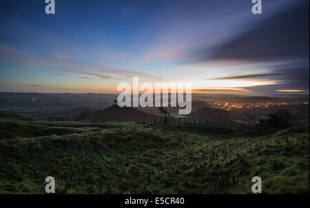 Beau lever de l'aube paysage de campagne avec vue sur la ville illuminée dans la vallée ci-dessous Banque D'Images