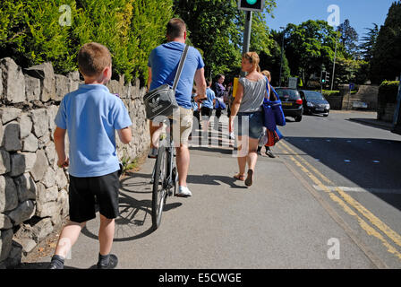 Maidstone, Kent, Angleterre. Boy walking accueil de l'école primaire et le cycliste sur la chaussée Banque D'Images