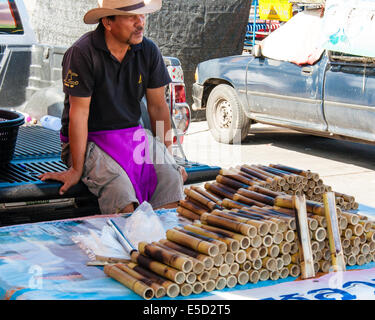 Vendeur de rue de riz collant dans les joints du bambou près de célèbre marché ferroviaire Maeklong, Thaïlande Banque D'Images