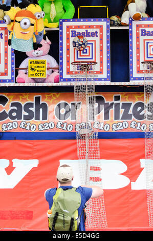 L'homme jette un terrain de basket-ball à travers un cerceau à un champ de foire Banque D'Images