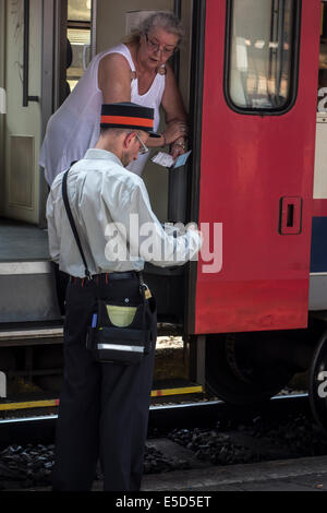 Femmes âgées demandent à l'information des passagers de l'employé de chemin de fer / ticket inspecteur de train sur plate-forme en railroad station Banque D'Images