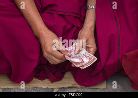 Les mains d'un moine bouddhiste, en comptant l'argent, tôt le matin à la célèbre stupa bouddhiste de Botnath (Bouddhanath), au Népal. Banque D'Images