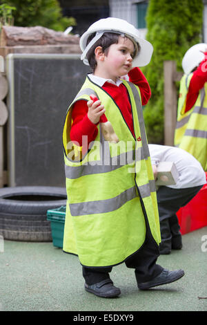 Un garçon faisant semblant d'être un constructeur à un UK nursery school Banque D'Images