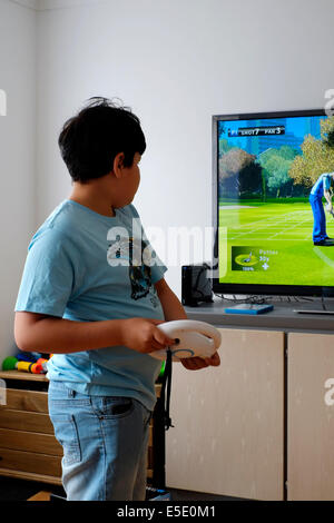 Jeune garçon, jouer en face de grand écran avec nintendo wii à la maison Banque D'Images