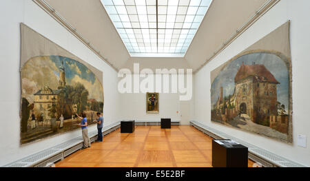 La peinture monumentale 'Das Residenzschloss mit Bastille und Anna à Weimar' (Château de Weimar à Bastille et la tour) par Max Martini (1867-1920) est retouché par l'historien de l'art Anne Schwarzback et restaurateur Peter Jung dans la Kunsthalle Harry Graf Kessler dans le Musée Municipal de Weimar, Allemagne, 29 juillet 2014. À droite est la peinture de Martini 'Die Wartburg bei Eisenach (Blick auf das von Nordosten Torhaus und die Burg)' (le près de Wartburg Eisenach (vue de l'northease vers le Gate House et le Fort)). Les tableaux font partie de l'exposition 'Aus dem alten Weimar - Monum Banque D'Images