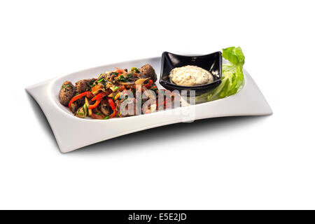 Les boulettes de viande et de légumes sur une assiette décorée avec de la sauce isolated on white Banque D'Images