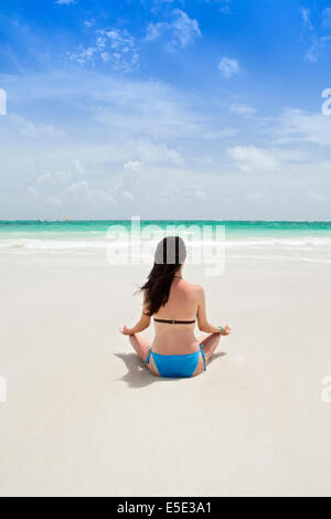 Une jeune femme méditant sur une plage des Caraïbes Banque D'Images