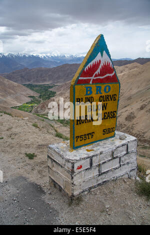 Signe lumineux au premier plan sur l'un des plus traître passe de montagne plein de virages aveugles . Vallée verte au loin. Ladakh, Inde Banque D'Images