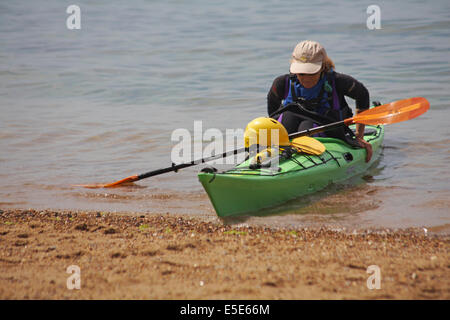 Femme sortir de kayak dans la mer à Worbarrow Bay, à l'île de Purbeck, Dorset en Juillet Banque D'Images