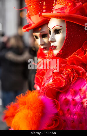 Rouge vif et costumes à froufrous ornent deux femmes à st. la place Saint-Marc à Venise pendant le carnaval. Banque D'Images