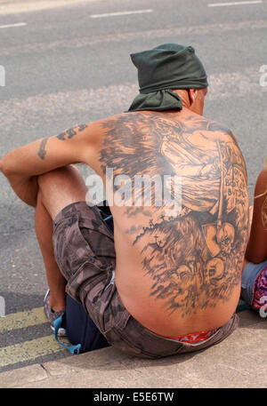 Homme assis sur la chaussée avec des tatouages sur son dos, mon corps gisait encore mais je errer, à Swanage, Dorset en Juillet Banque D'Images