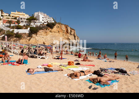 Les gens à prendre le soleil sur des vacances sur la plage de Carvoeiro, Algarve, Portugal Europe Banque D'Images