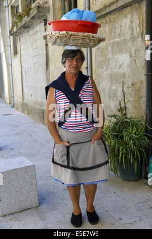 Femme portugaise exerçant son panier à linge sur la tête. Banque D'Images