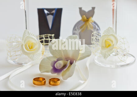 Deux anneaux de mariage sur fond blanc avec des orchidées Banque D'Images