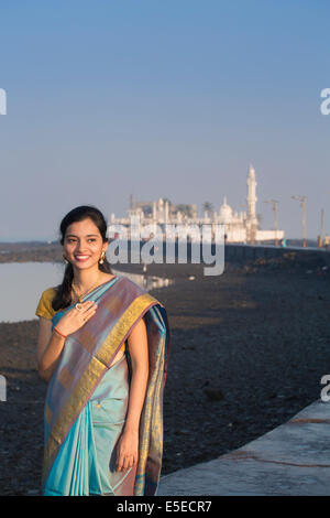 Une jeune femme dans un saree bleu sur la chaussée à la mosquée Haji Ali, Mumbai, Maharashtra, Inde Banque D'Images