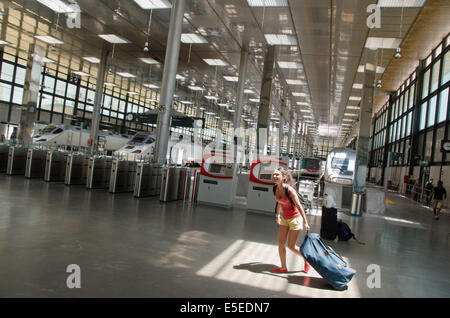 Une jeune femme s'empresse de voyageurs à travers la gare de Cadix avec ses bagages. Banque D'Images