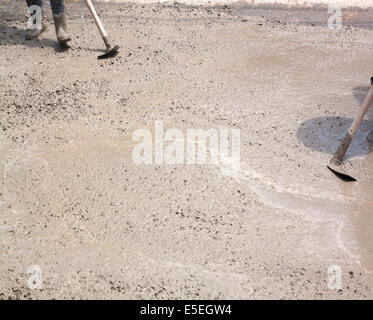 Coulage du béton au cours de travaux de bétonnage des sols ; le compactage du ciment liquide manoeuvre en forme de renfort travailler Banque D'Images