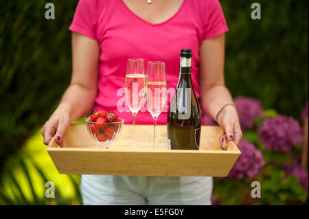 Femme tenant un plateau avec champagne et fraises Banque D'Images