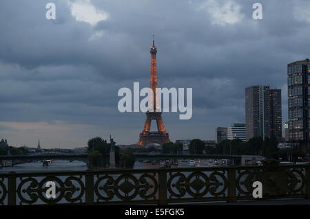 La Tour Eiffel de nuit, éclairés avec des lumières orange, avec la réplique de la Statue de la Liberté au premier plan Banque D'Images