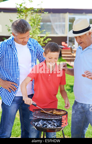 Saucisses à frire Cute boy avec son grand-père et père près de par Banque D'Images