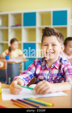 Portrait of a cute schoolboy looking at camera sur fond de ses camarades Banque D'Images