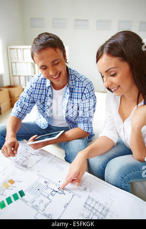 Portrait of young couple discutant du plan new flat Banque D'Images