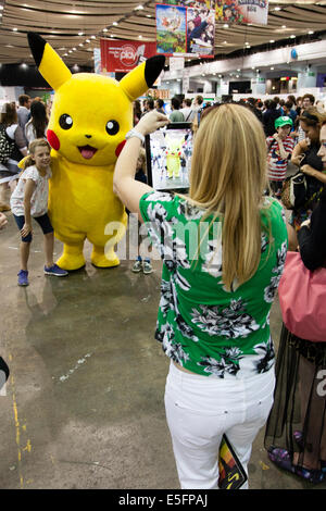 Londres, Angleterre un visiteur au Japon Hyper dans Earls Court prend une photo d'une jeune fille serrant Pikachu avec son iPad. Banque D'Images