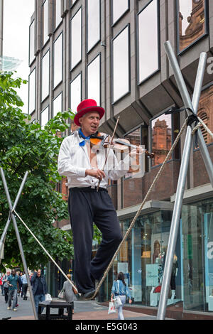 La lecture d'un musicien ambulant de rue lors de l'exécution d'un violon sur le trapèze, Buchanan Street, Glasgow, Royaume-Uni Banque D'Images