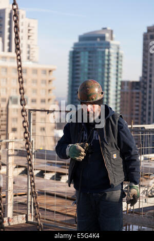 Un travailleur de la construction des montres une charge complète de béton a été levé à un site de construction sur le toit à Toronto, Ontario, Canada. Banque D'Images
