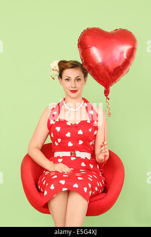 Femme en robe rouge holding heart shaped balloon