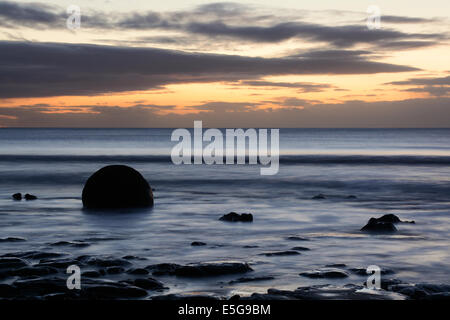 Lever du soleil sur la plage avec un Koekohe Moeraki Boulder Banque D'Images