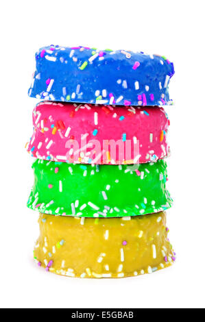 Un tas de donuts recouverts de givre et saupoudre de différentes couleurs sur un fond blanc Banque D'Images