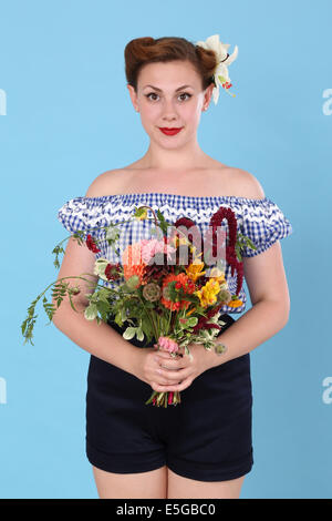 Femme dans un haut imprimé vichy tenant un bouquet de fleurs Banque D'Images