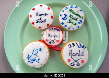 Cup cakes sur une plaque avec les titres de certaines pièces de Shakespeare dans des écrits à une foire d'été, râteau, Hampshire, Royaume-Uni. Banque D'Images