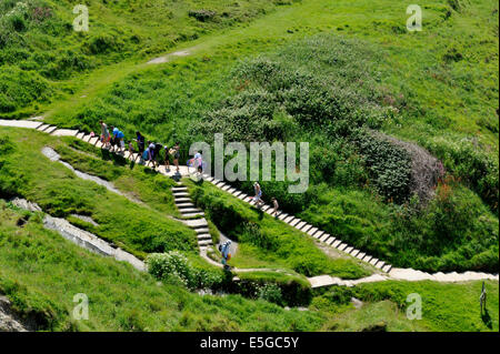 Chemin et d'opérations entre les collines verdoyantes à Mwnt beach avec des gens Banque D'Images