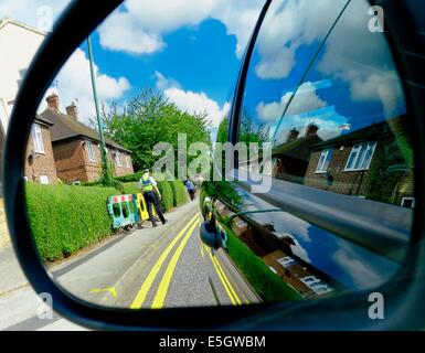 Rétroviseur voiture montrant un agent de soutien communautaire de la police patrouille dans une rue de Nottingham England uk Banque D'Images