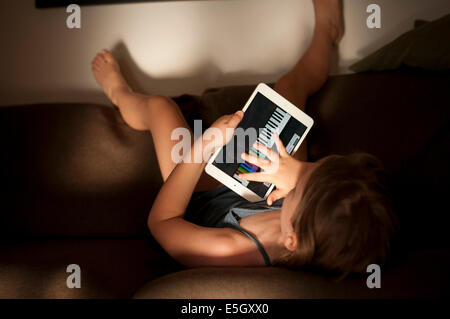 Fillette de six ans à l'aide d'un ipad mini ordinateur à la maison. Banque D'Images