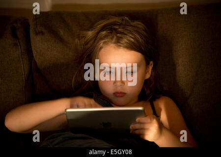 Fillette de six ans à l'aide d'un ipad mini ordinateur à la maison. Banque D'Images