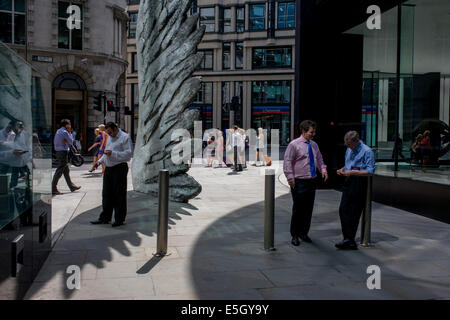 Les travailleurs de la ville de fumer des cigarettes par le géant de l'oeuvre une aile de bronze lors d'un midi de printemps dans le quartier financier de Londres. Comme la lumière se reflète sur les immeubles de bureaux à proximité, la foule à l'heure du déjeuner devant ce géant des illustrations sur leur façon de réunions et sandwicheries. Les dix mètres de haut est la sculpture en bronze par le président de la Royal Academy of Arts, Christopher Le Brun, commandé par Hammerson en 2009. Elle est appelée 'La Ville' de l'aile et a été jeté par Morris Singer, fondateurs de l'art réputé pour être la plus ancienne fonderie d'art dans le monde. Banque D'Images