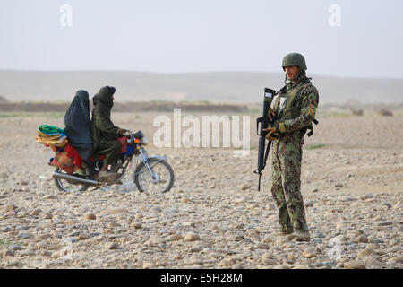 Les civils afghans ride au-delà d'un soldat de l'Armée nationale afghane avec le 4e, 6e Kandak Tolay, 6e Brigade, 215e Corps comme il provi Banque D'Images