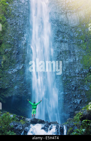 Homme debout à la base de grande cascade à Hawaï Banque D'Images